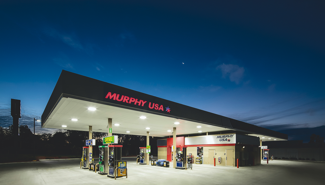 A brightly lit Murphy USA gas station at twilight under a deep blue sky with a crescent moon overhead.