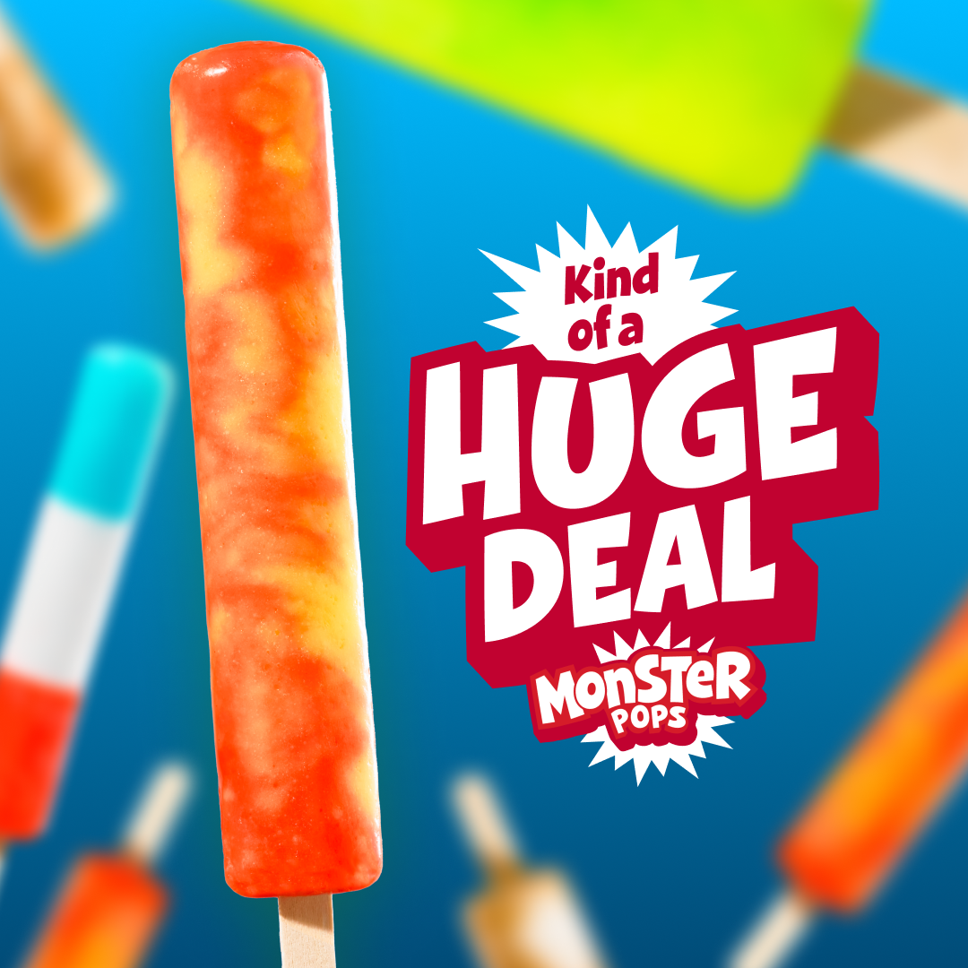 A long, vibrant orange and yellow swirled ice pop stands upright against a bright blue background. Next to the popsicle is stylized bold text reading 'Kind of a HUGE DEAL' above the 'MONSTER POPS' logo. Out-of-focus colorful popsicles float in the background.